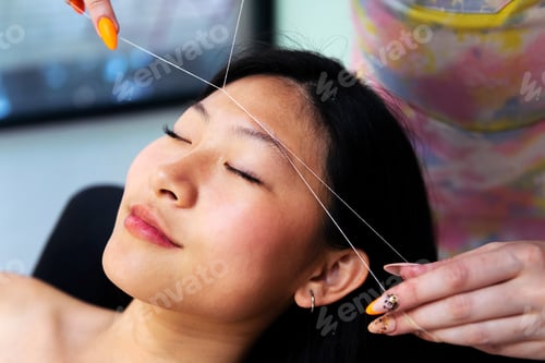 Preview: beautician performs eyebrow threading on a woman