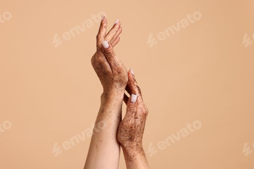 Preview: Woman applying body scrub onto her hands on beige background, closeup