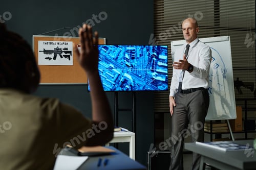 Preview: Bald mature officer pointing at student raising her hand at lesson