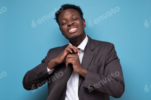 Preview: Frustrated african businessman untying tie after hard working day.