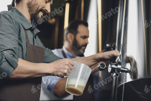 Preview: Male brewery worker pouring beer from the tank
