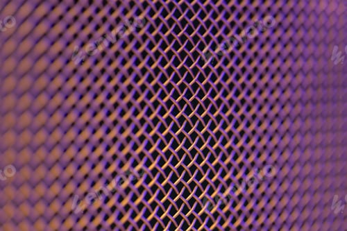 Preview: Metal grill close-up, texture of a music speaker in colored lighting.