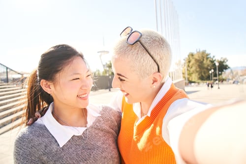 Preview: Selfie of an interracial lesbian happy couple. Smiling Asian woman and a cheerful Caucasian girl
