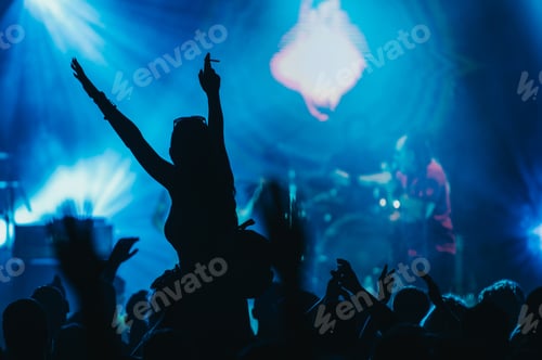 Preview: Silhouette of a woman with raised hands on a concert