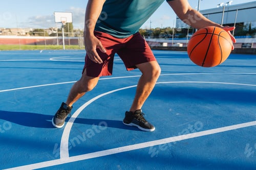 Preview: Young adult playing basketball dribbling on blue court