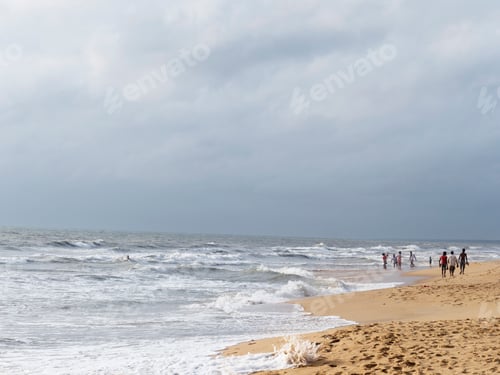 Preview: Strollers and a lone surfer enjoying a serene beachscape.
