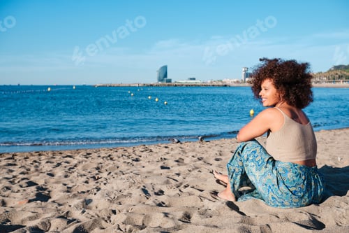 Preview: young afro curvy woman at Barcelona beach in a summer day