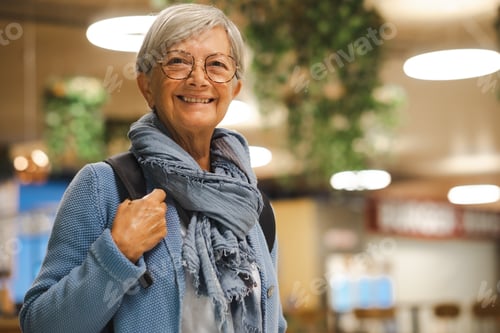 Preview: Smiling senior caucasian traveler woman with backpack at the airport gate waiting for departure