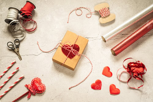 Preview: Valentine's day gift wrapping supplies and gift box with sequin heart on gray stone background
