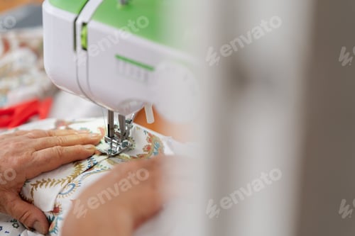 Preview: Hands of an Unrecognizable Senior Woman Sewing Patterned Fabric on Machine
