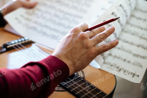 Preview: Man hands with sheet music playing guitar