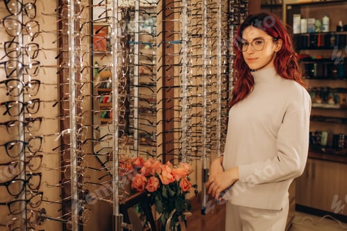 Preview: Young smiling woman choosing a new pair of prescription glasses at the eyewear store