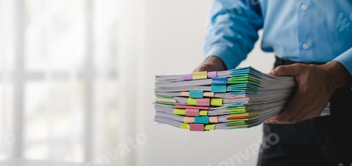 Preview: Businessman working on stacks of documents to search for information and check documents on office d