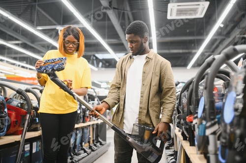 Preview: African american couple crouching and looking at vacuum cleaner they want to buy.
