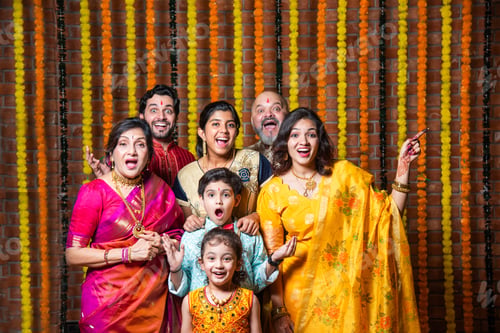 Preview: Indian family with grandparents and kids, excited and pointing in traditional Diwali attire