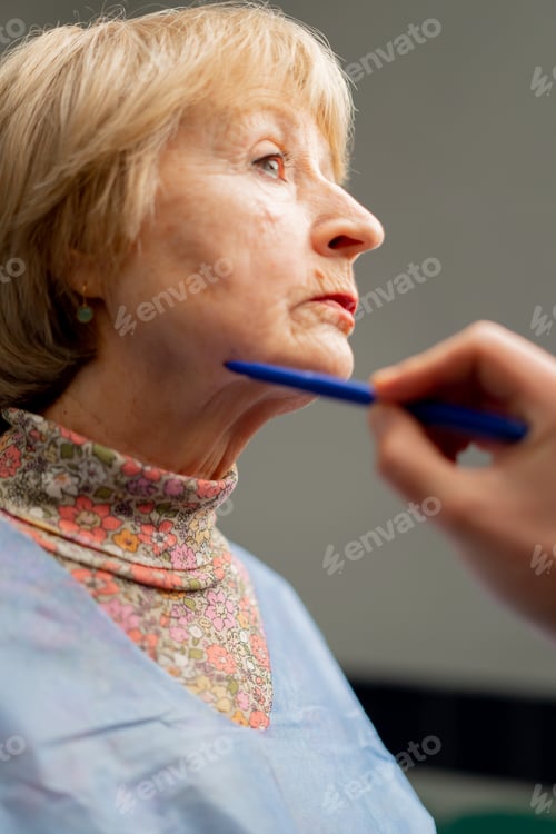 Preview: plastic surgery clinic a doctor makes markings on the face of an elderly woman before a facelift