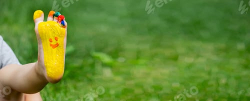 Preview: The child was lying on the green grass. Smile with paints on the legs and arms.