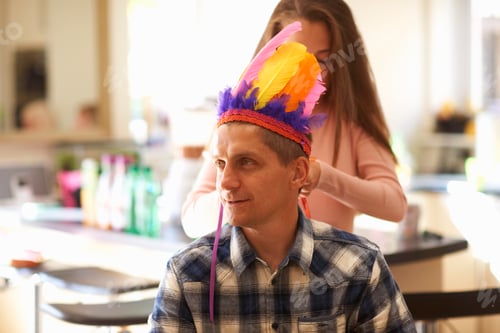Preview: Girl putting feather headdress on father