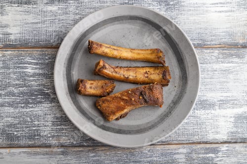 Preview: pork ribs on a wooden plate on a gray. Top view.