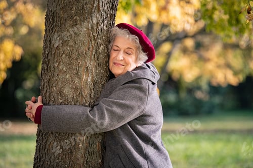 Preview: Senior woman hugging tree