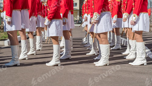 Preview: Organized group of girls in bright ceremonial costumes march along city street with drumsticks