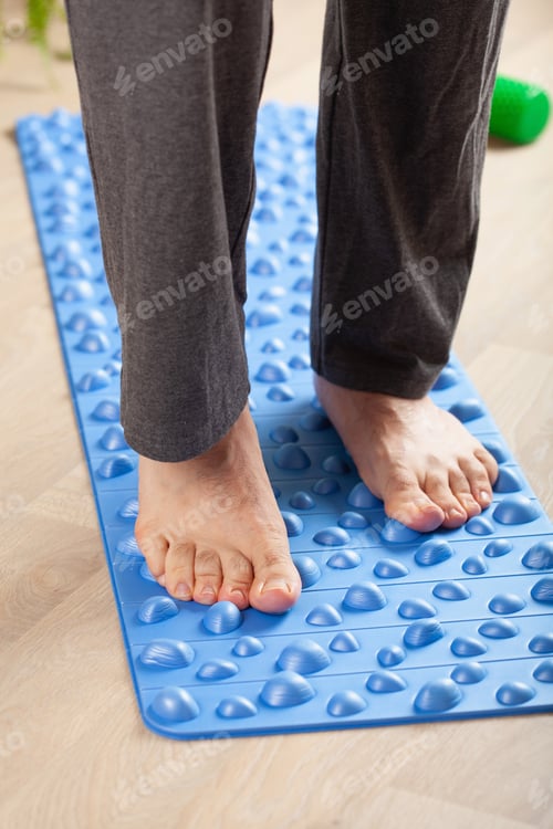 Preview: man doing flatfoot correction gymnastic exercise walking on massage mat at home