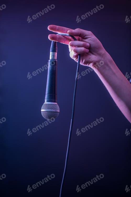 Preview: hand with microphone on a black background, the music concept, beautiful lighting on the stage