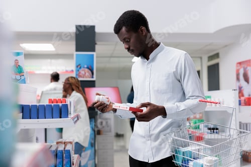 Preview: African american man checking food supplements in drugstore shelf