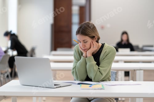 Preview: Upset female mature-age student working on difficult homework in library, tired of studying