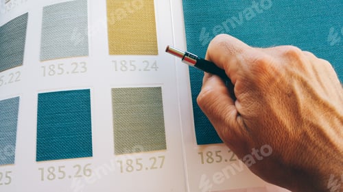 Preview: Architect with a color card selecting finishes. Focus on hand and pencil