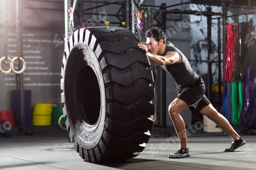 Preview: Young man pushing large tire in crossfit gym