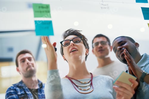 Preview: Shot of a group of designers brainstorming with notes on a glass wall in an office