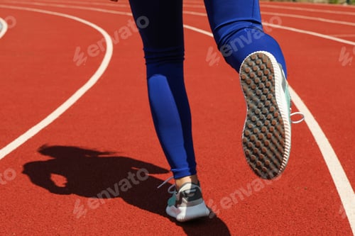 Preview: Girl running on red athletic track. Sport concept