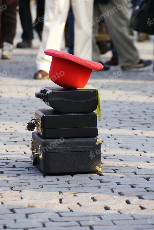Preview: Red hat on old suitcases placed by a street performer in the street to perform a show.