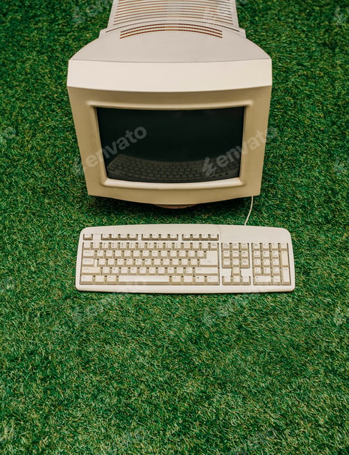 Vista previa: Vintage PC on green grass, top view. Monitor and keyboard as in 90s
