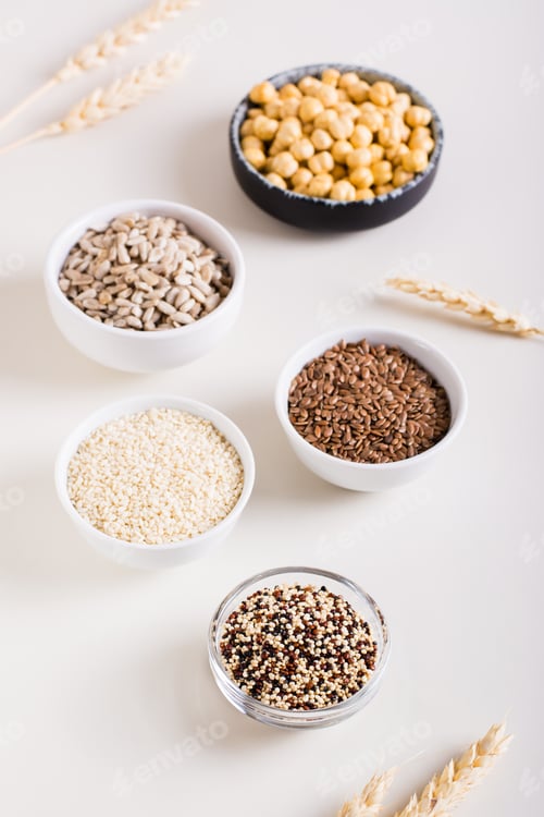 Preview: Quinoa, sesame, flax seeds, sunflower seeds and chickpeas in bowls on the table. Vertical view