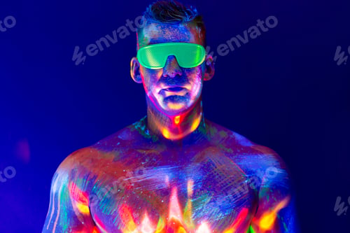 Preview: Portrait of a pumped-up man at a disco. Fluorescent paint on face in with UV light.