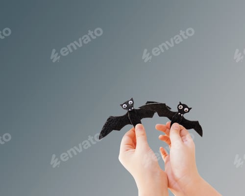 Preview: childs hands holding two model bats, halloween
