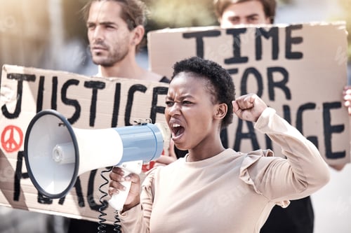 Preview: No more excuses. Shot of a young woman shouting through a megaphone at a protest.