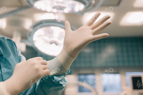 Preview: A close up shot of a doctor’s hands as they carefully put on surgical gloves in surgery