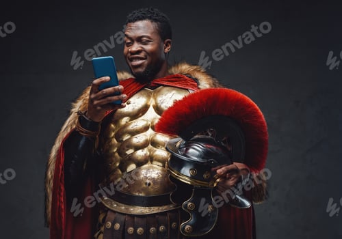 Joyful black man in roman soldier costume using smartphone