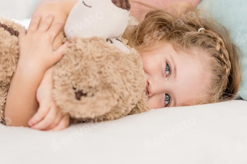Preview: cheerful adorable kid hugging teddy bear on bed in children room