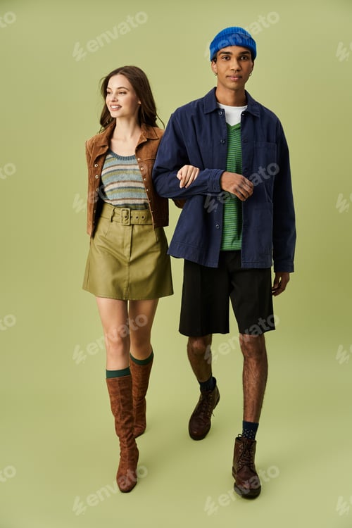 Preview: Stylish young couple embraces autumn vibes in vibrant attire against a soft green backdrop