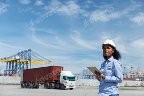 Preview: A female logistics officer in a hard hat observes cargo operations at a shipping port.