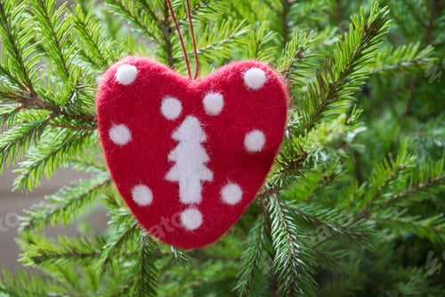 Preview: Christmas tree with handmade red felt heart as decor. Xmas card. Close up. Copy space. Winter.