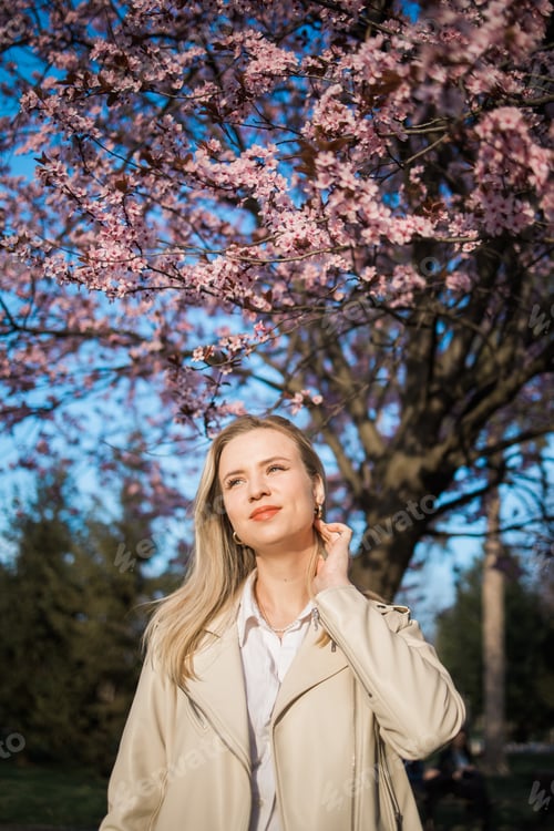 Preview: Woman with cherry flowers surrounded by blossoming trees copy space. Beauty and seasonal change and
