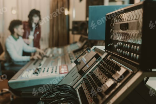 Preview: close-up shot of sound amplifiers at recording studio with blurred producers behind