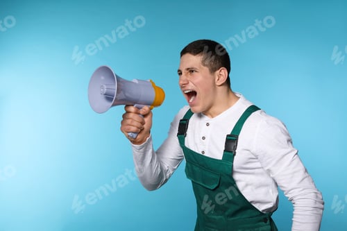 Preview: Portrait of emotional male worker using megaphone on color background