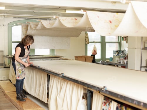 Preview: Woman working by drying system in hand-printing textile workshop