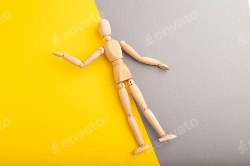 Preview: Wooden mannequin lies on gray and yellow pastel background. copy space.